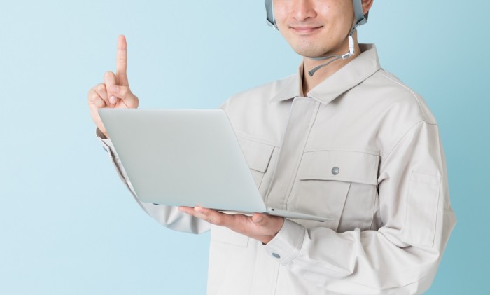 パソコンを持つ作業服の男性